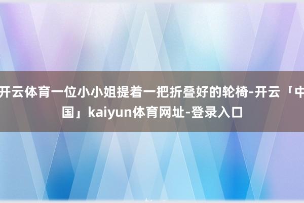 开云体育一位小小姐提着一把折叠好的轮椅-开云「中国」kaiyun体育网址-登录入口